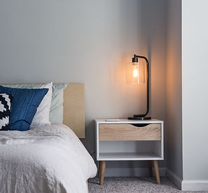 Une table de chevet avec tiroir proche d'un lit